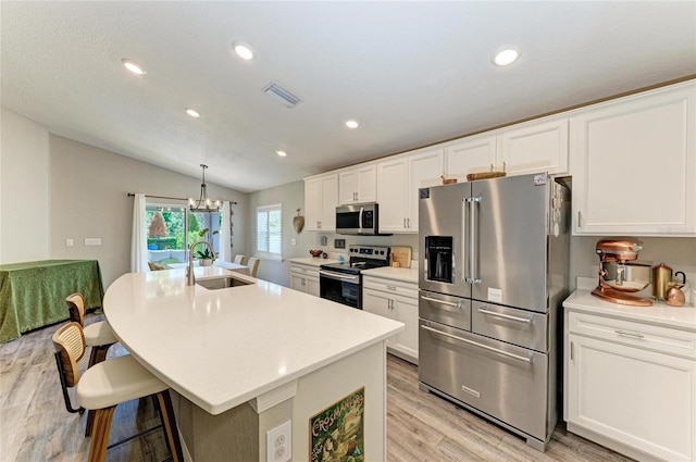 kitchen featuring a sink, stainless steel appliances, an island with sink, and light countertops