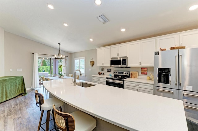 kitchen featuring visible vents, appliances with stainless steel finishes, light countertops, white cabinetry, and a sink