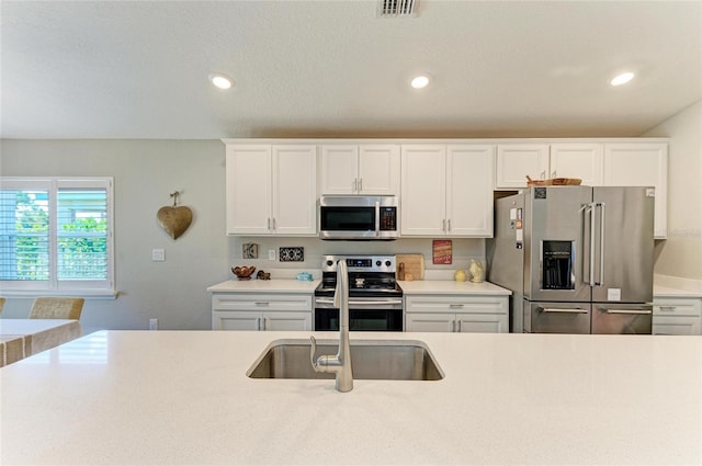 kitchen featuring visible vents, white cabinets, stainless steel appliances, light countertops, and recessed lighting