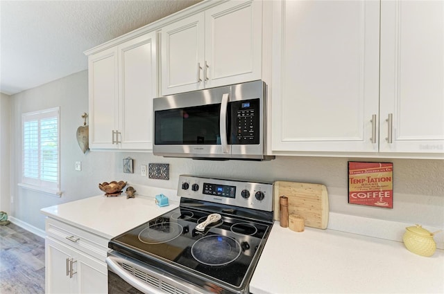 kitchen with white cabinets, wood finished floors, stainless steel appliances, a textured ceiling, and light countertops