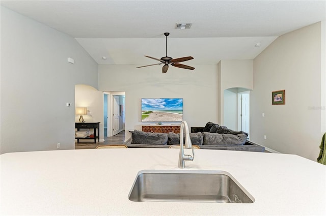 kitchen featuring arched walkways, light countertops, visible vents, open floor plan, and a sink