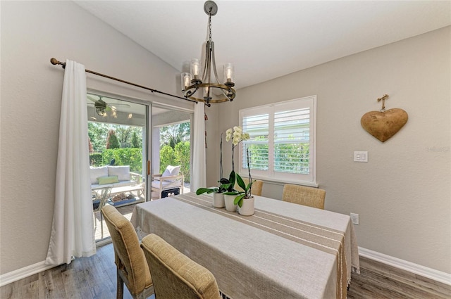 dining space with vaulted ceiling, an inviting chandelier, wood finished floors, and baseboards