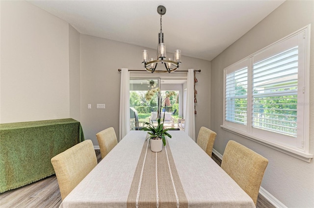 dining room featuring baseboards, vaulted ceiling, wood finished floors, and an inviting chandelier