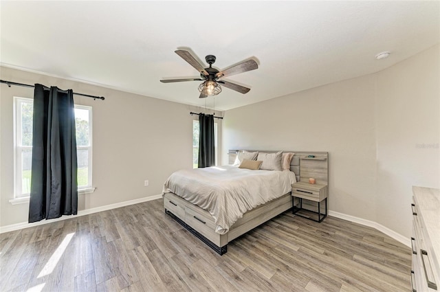 bedroom with light wood-style floors, ceiling fan, and baseboards