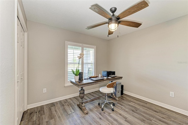 office space with baseboards, ceiling fan, and light wood-style floors