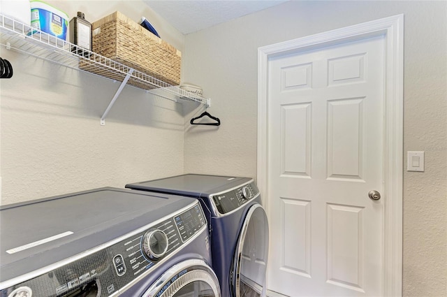 clothes washing area featuring a textured wall, laundry area, and independent washer and dryer