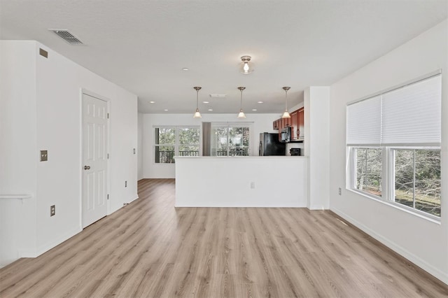 unfurnished living room featuring light wood-style flooring, visible vents, and baseboards