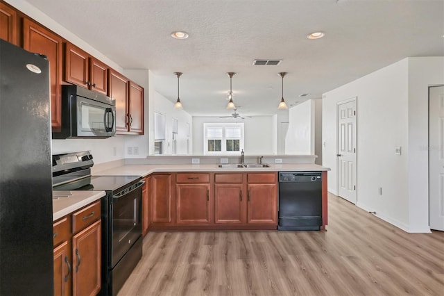 kitchen featuring decorative light fixtures, light countertops, a sink, a peninsula, and black appliances