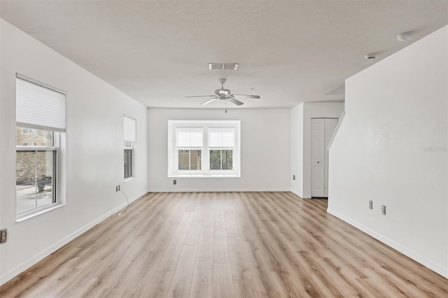 unfurnished living room with visible vents, plenty of natural light, light wood-style flooring, and baseboards