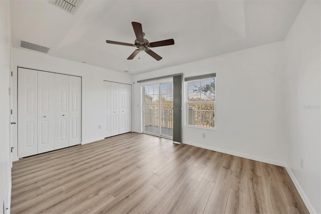 unfurnished bedroom featuring access to outside, two closets, visible vents, and light wood-style floors