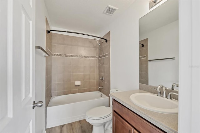 bathroom with toilet, wood finished floors, bathing tub / shower combination, vanity, and visible vents