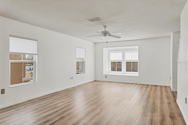 spare room featuring light wood finished floors, a textured ceiling, baseboards, and a ceiling fan