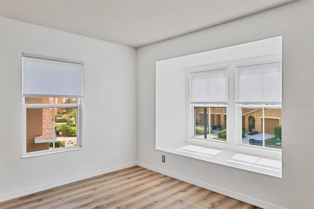 unfurnished room with light wood-type flooring and baseboards