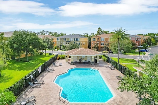 community pool featuring a residential view, fence, and a patio