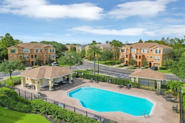 community pool featuring a residential view, fence, and a patio