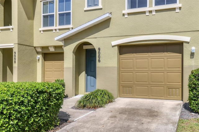 property entrance featuring a garage, driveway, and stucco siding