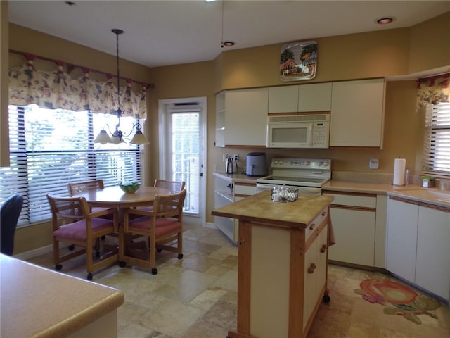 kitchen featuring white appliances, butcher block countertops, a center island, decorative light fixtures, and white cabinetry