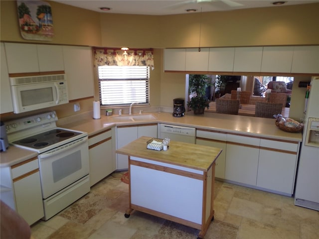 kitchen featuring stone finish floor, white appliances, white cabinets, and a sink