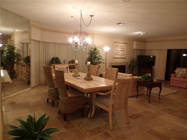 dining space featuring crown molding, a notable chandelier, visible vents, stone finish floor, and a tile fireplace