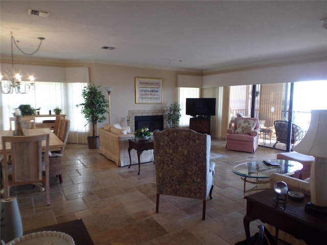 living area with crown molding, a fireplace, stone tile floors, and a wealth of natural light