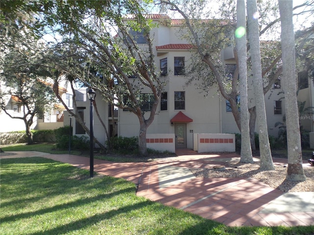 view of front of home with a tiled roof, a front yard, and stucco siding