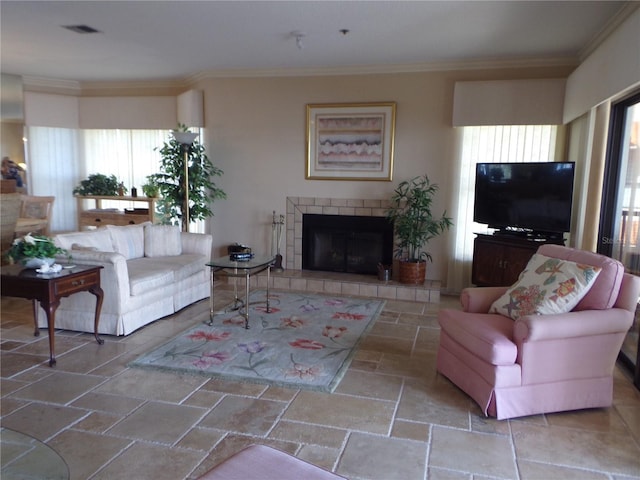 living area featuring ornamental molding, stone tile flooring, visible vents, and a tiled fireplace