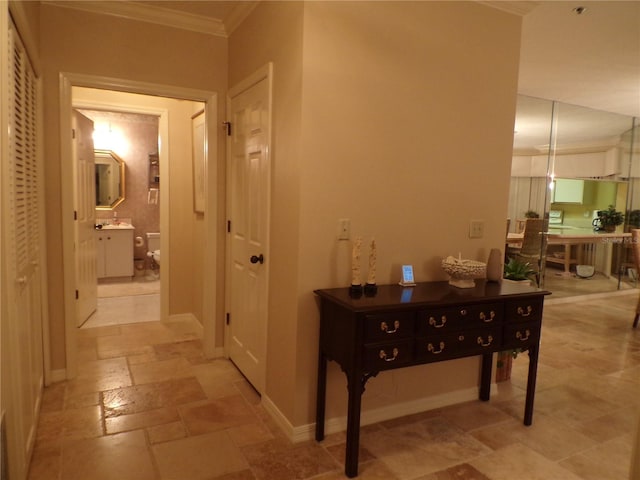 corridor with ornamental molding, stone tile flooring, and baseboards