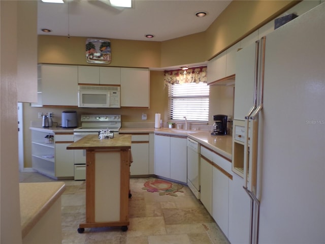 kitchen with white appliances, white cabinets, a center island, wooden counters, and a sink