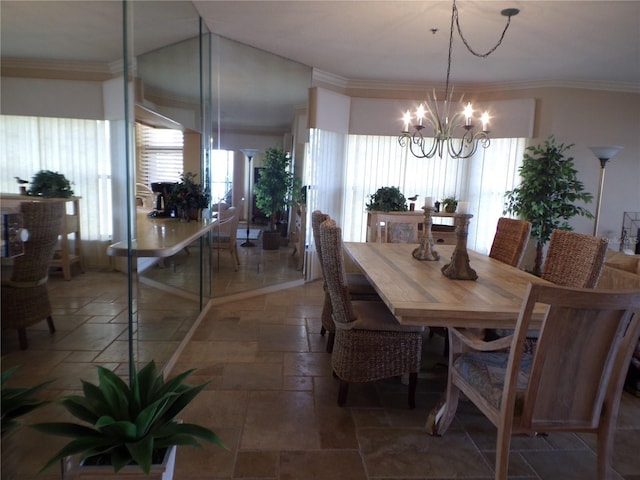 dining room featuring ornamental molding, stone tile flooring, and an inviting chandelier