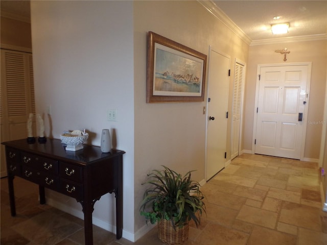 entrance foyer featuring baseboards, ornamental molding, and stone tile floors