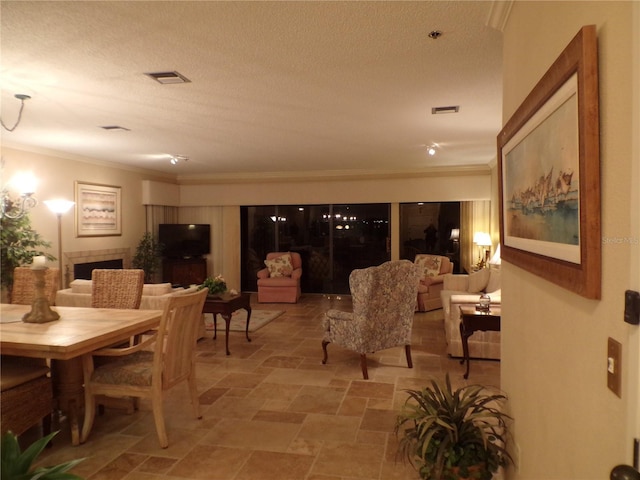 dining space featuring a fireplace, visible vents, ornamental molding, stone finish flooring, and a textured ceiling