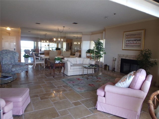 living area with stone finish floor, ornamental molding, a notable chandelier, and a tile fireplace