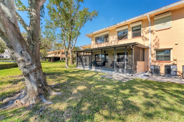 8140 Terrace Garden Dr N Unit 103, Saint Petersburg, FL 33709 - back of property featuring a sunroom, stucco siding, central air condition unit, and a lawn