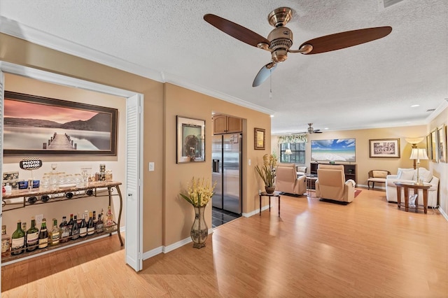 8140 Terrace Garden Dr N Unit 103, Saint Petersburg, FL 33709 - living room featuring ceiling fan, light wood-style flooring, crown molding, a textured ceiling, and baseboards