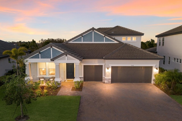 craftsman-style home featuring a garage, a tile roof, decorative driveway, and a front yard