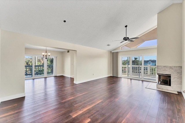 unfurnished living room featuring ceiling fan with notable chandelier, a stone fireplace, dark wood-type flooring, and lofted ceiling