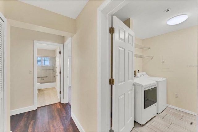 washroom featuring light wood finished floors, separate washer and dryer, baseboards, and laundry area