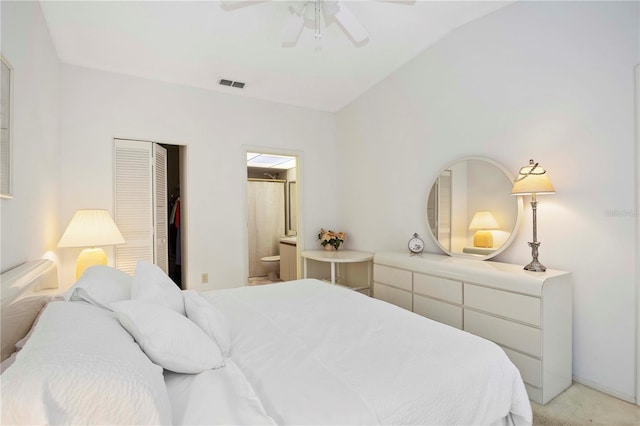 bedroom featuring visible vents, ceiling fan, light colored carpet, a closet, and ensuite bath