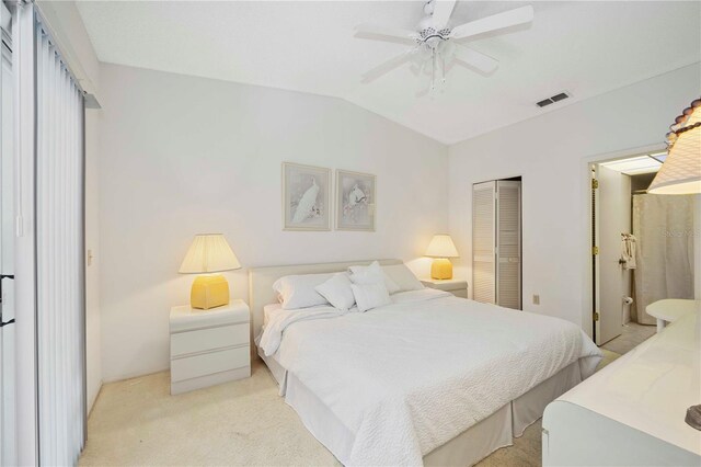 bedroom featuring visible vents, ensuite bath, vaulted ceiling, a closet, and light carpet