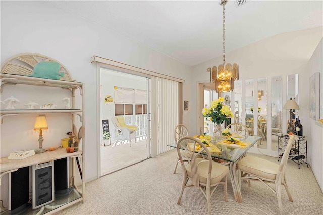 dining space with lofted ceiling, carpet floors, and an inviting chandelier