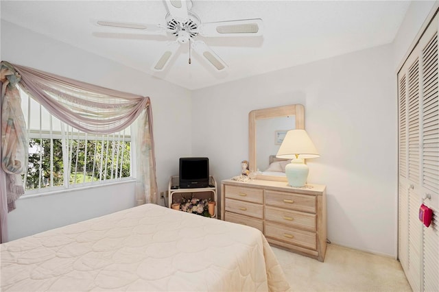 bedroom with light carpet, ceiling fan, and a closet