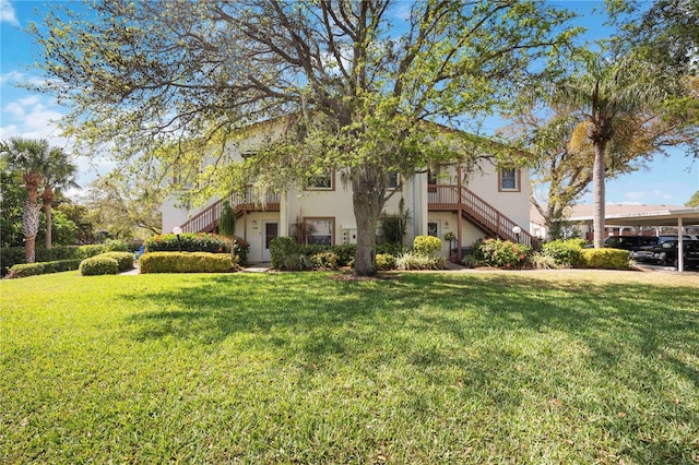 view of side of property featuring stairway, a yard, and stucco siding