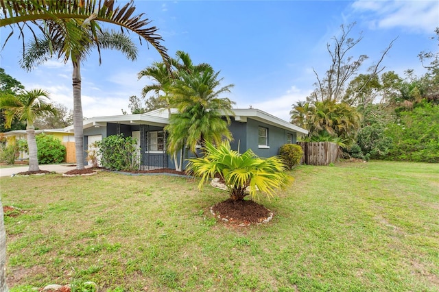 view of front of property featuring concrete driveway, an attached garage, fence, a front lawn, and stucco siding