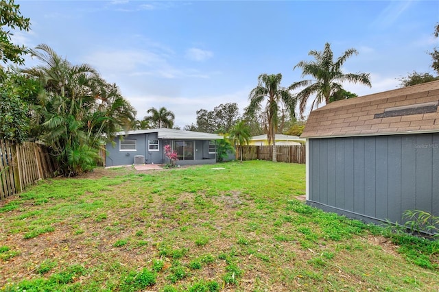 view of yard with an outbuilding, a fenced backyard, and a shed