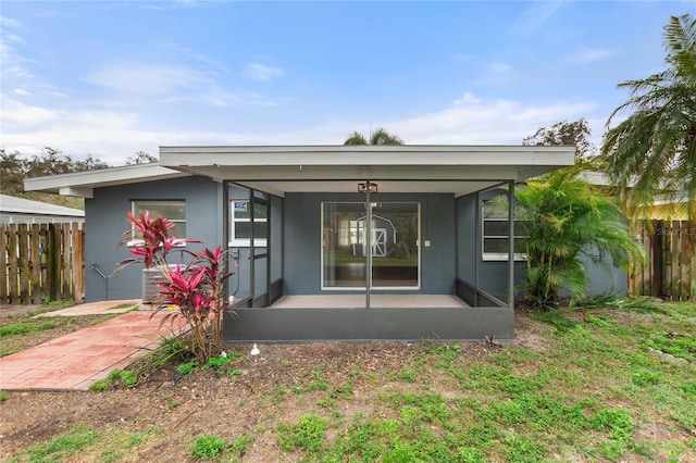 property entrance with a porch, fence, and stucco siding