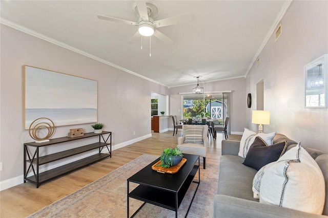 living room featuring baseboards, crown molding, visible vents, and wood finished floors