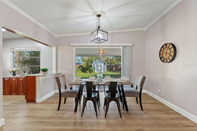 dining room featuring crown molding, light wood-type flooring, a notable chandelier, and baseboards