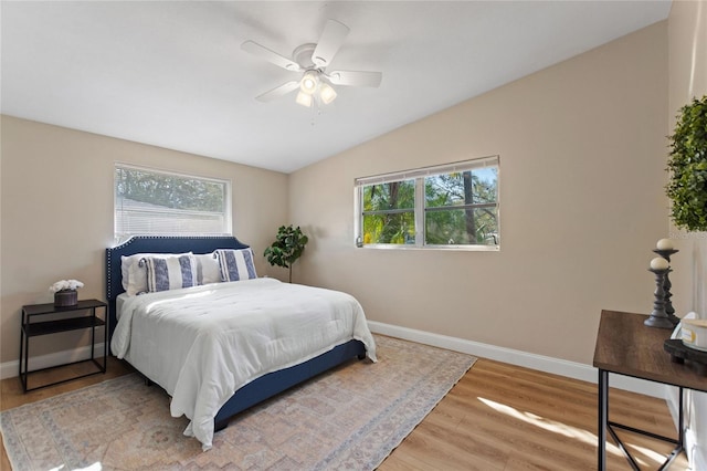 bedroom featuring vaulted ceiling, multiple windows, wood finished floors, and baseboards