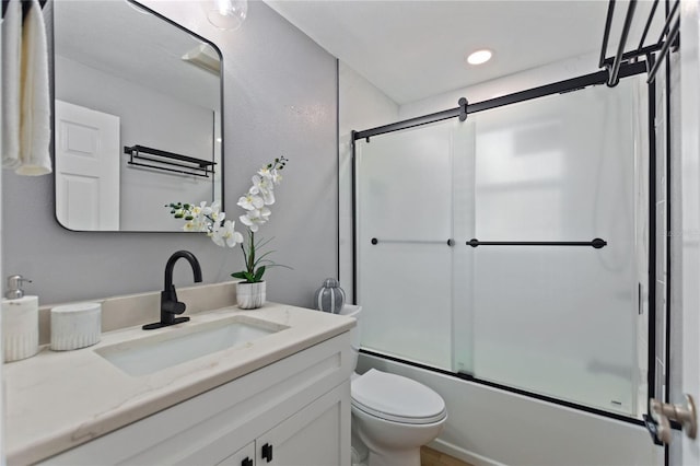 bathroom with toilet, combined bath / shower with glass door, and vanity