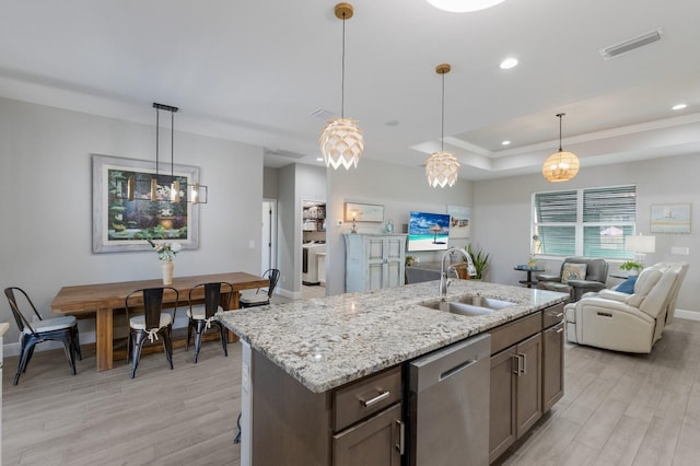 kitchen featuring dishwasher, a sink, visible vents, and light wood-style floors